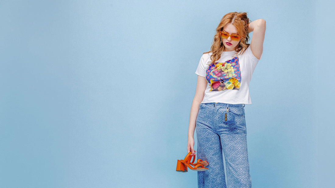 Model wearing the Tatiana Baby Tee, featuring a still life artwork print, photographed in a studio setting with soft, controlled lighting.
