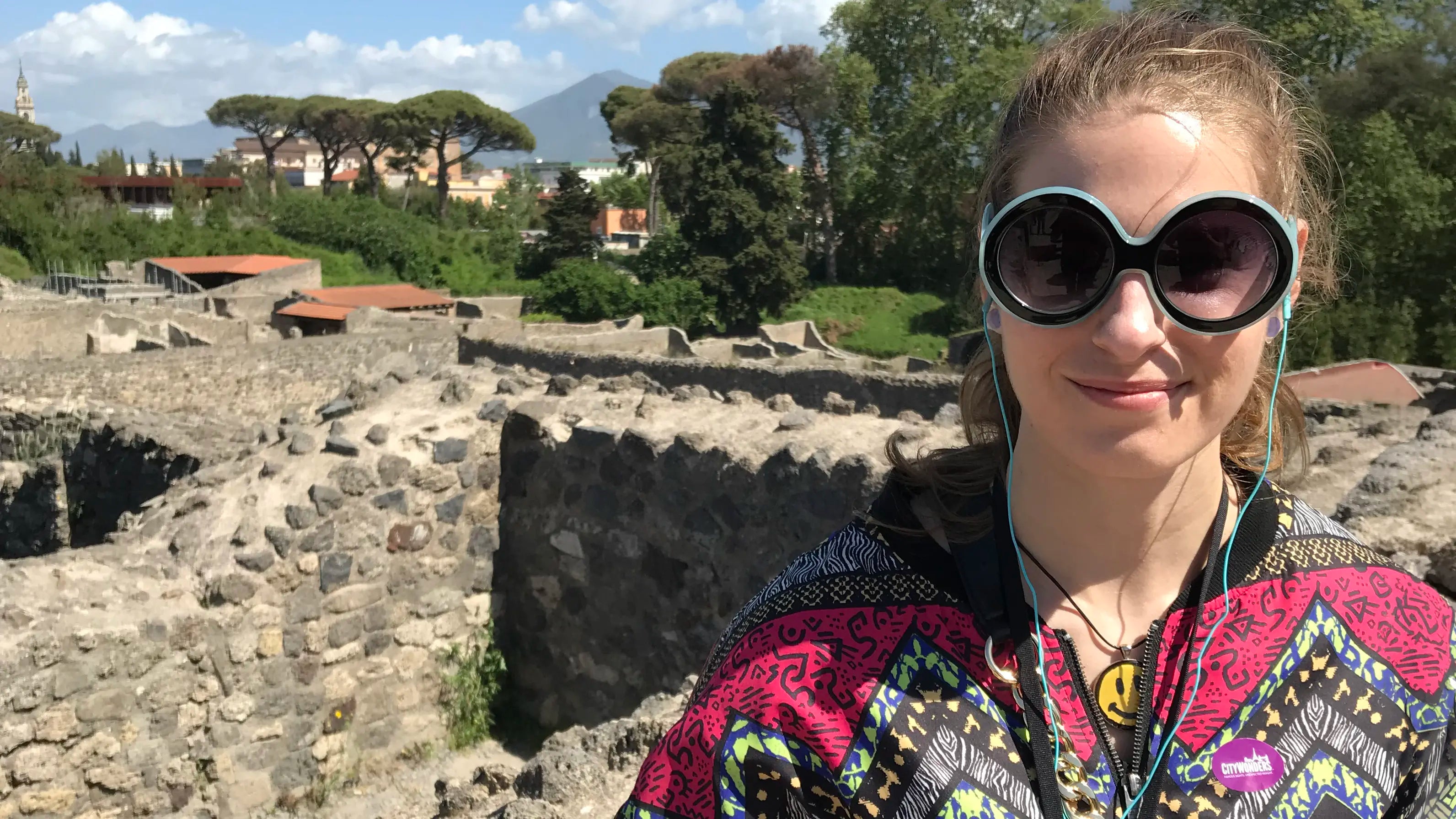Kaylie Caswell standing among the ancient ruins of Pompeii during a trip to Italy, with Mount Vesuvius visible in the distance.