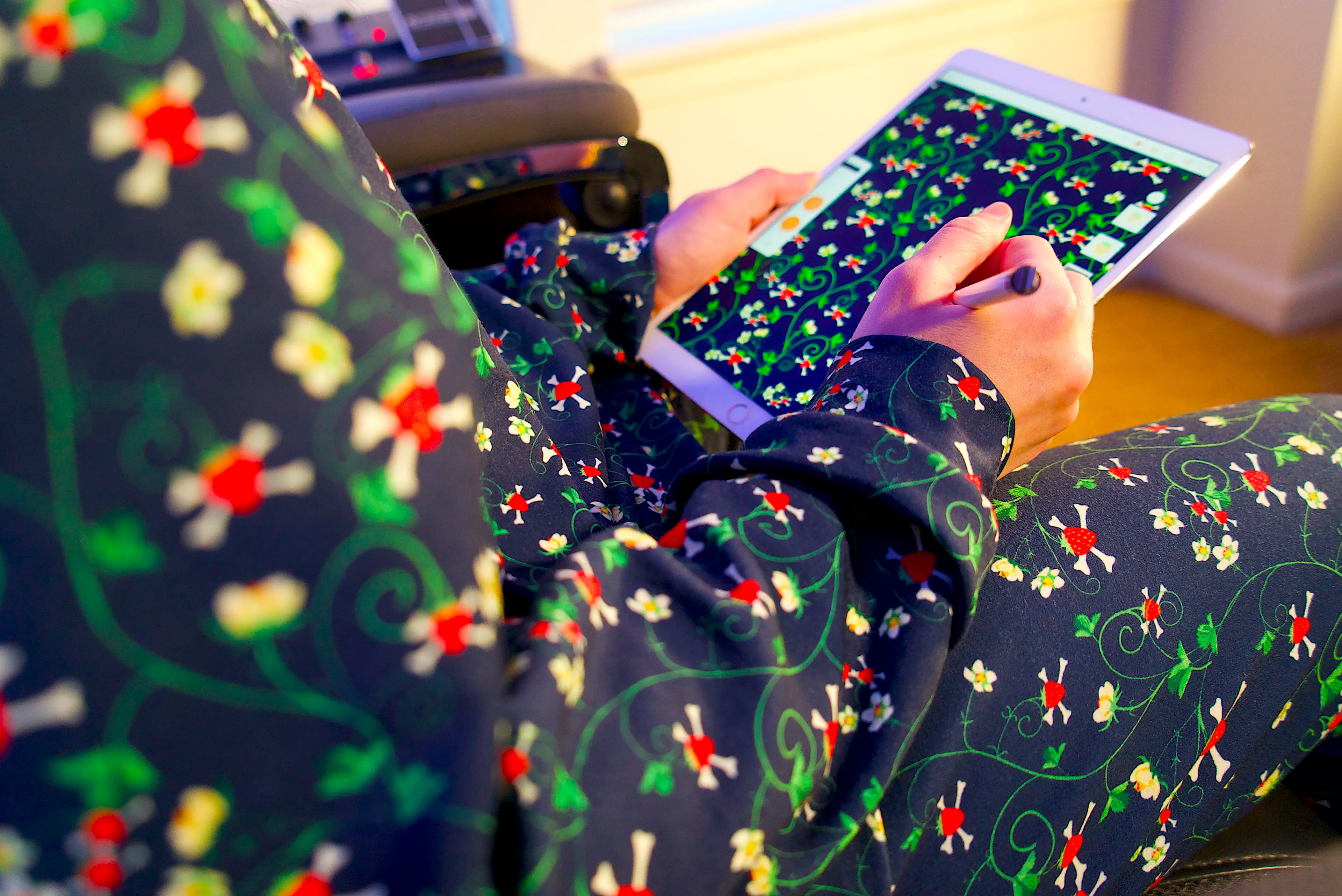 Designer drawing a repeating floral print on an iPad while wearing a matching custom printed garment.