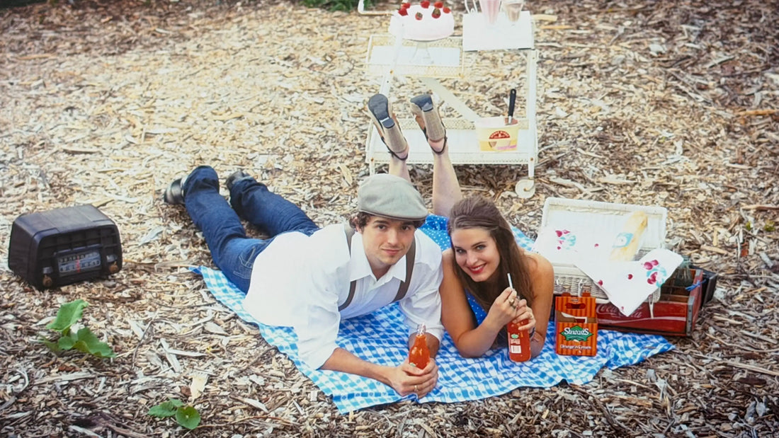 Couple on a picnic with fruit drinks and vintage styling, reflecting the visual language behind the House of Caswell Still Life collection