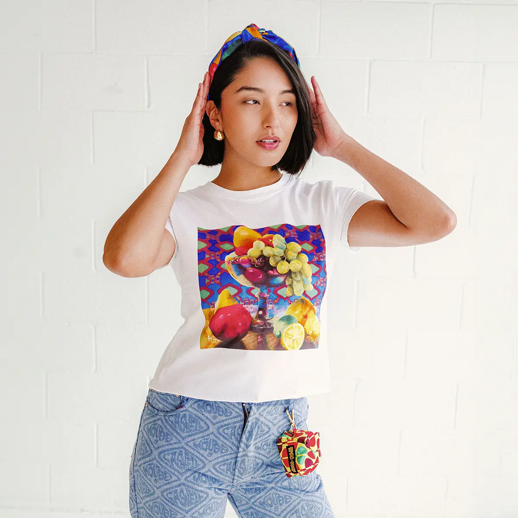 Woman wearing an art printed white baby t-shirt and printed jeans, with a silk turban headband and a printed charm bag clipped to her belt loop